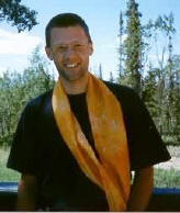 Dieses Foto zeigt mich, wie ich in Canada morgends auf der Veranda in der Sonne stehe. Im Hintergrund sind einige Bäume zu sehen.